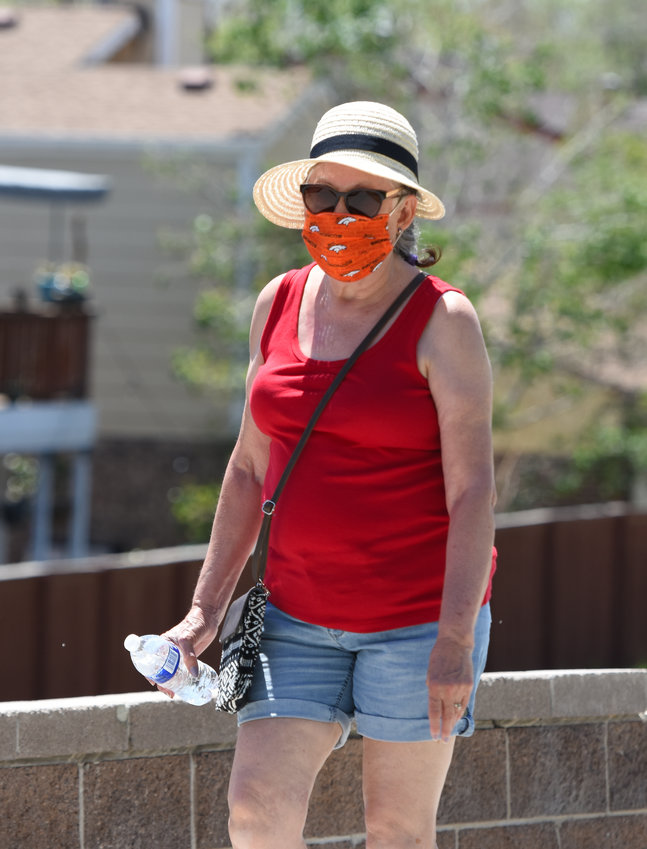 Loretta Johnson of unincorporated Adams County wears a mask as she walks around Webster Lake at E. B. Rains, Jr. Memorial Park in Northglenn on Tuesday, May 19.